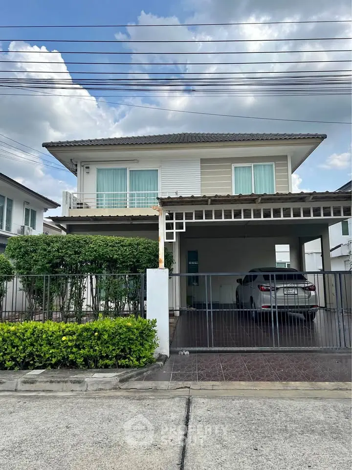 Charming two-story house with carport and lush greenery in a serene neighborhood.