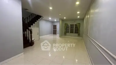 Spacious living room with elegant staircase and large window, perfect for family gatherings.