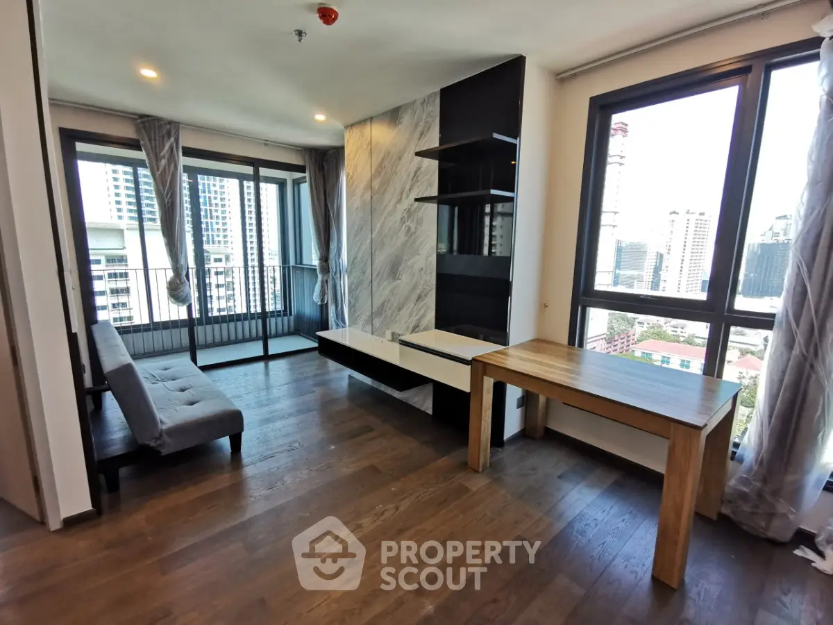 Modern living room with large windows and city view, featuring stylish decor and wooden flooring.
