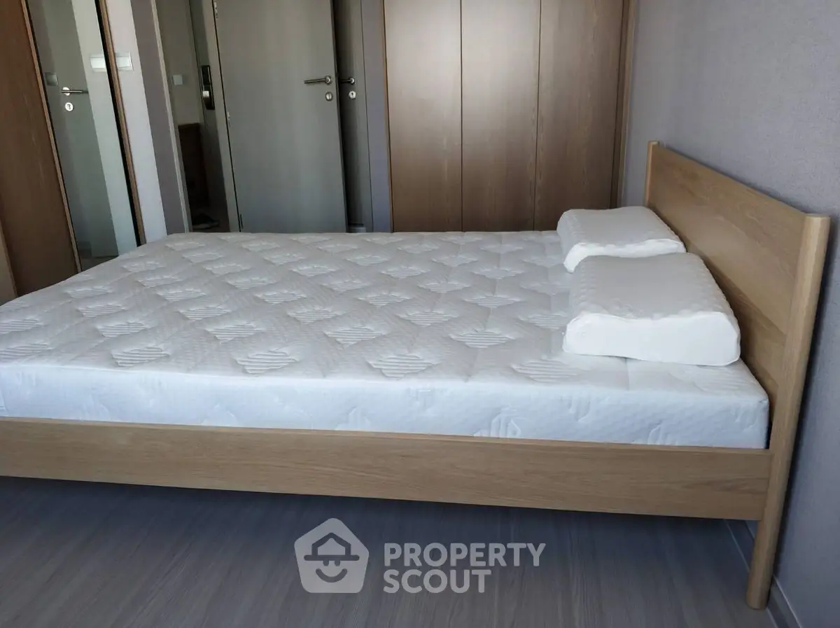 Spacious bedroom with modern wooden bed frame and comfortable mattress