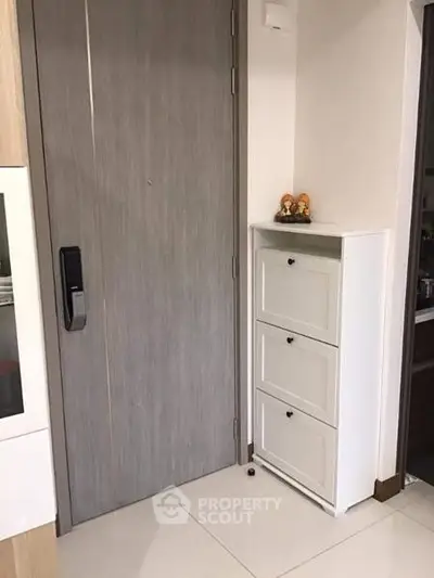 Modern apartment entrance with sleek wooden door and compact white storage unit.