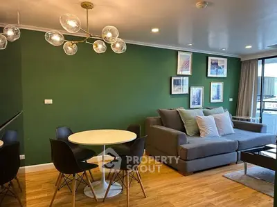 Stylish living room with modern decor and green accent wall, featuring a cozy seating area and elegant lighting.