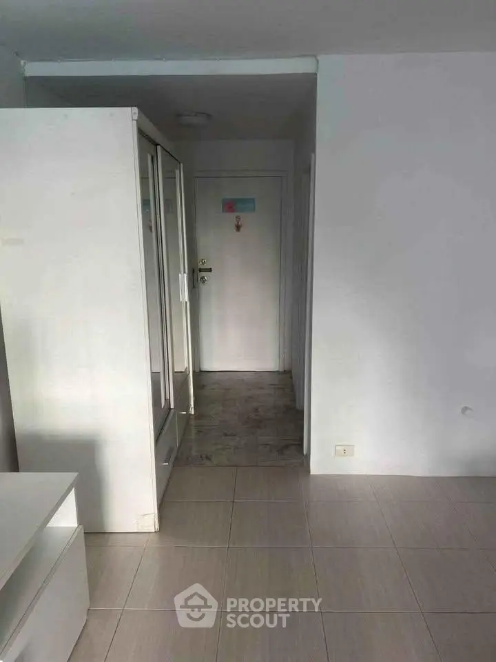 Spacious entryway with mirrored closet doors and tiled flooring in modern apartment.