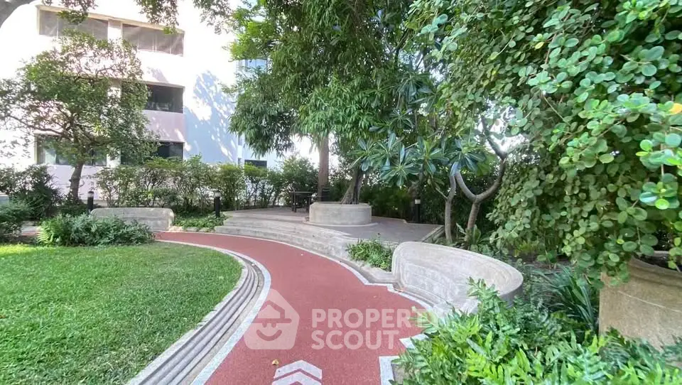 Beautiful garden pathway in residential complex with lush greenery and modern architecture.