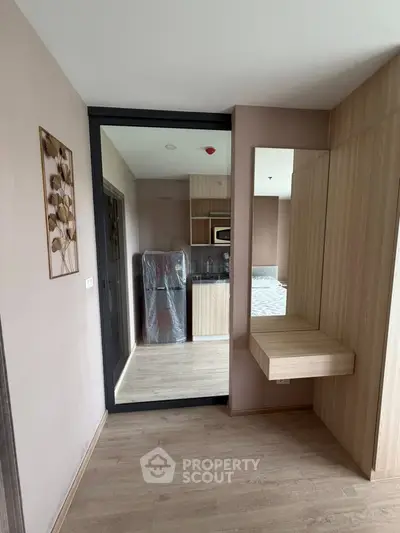 Modern apartment interior with wooden flooring and compact kitchen area, featuring sleek cabinetry and contemporary design.