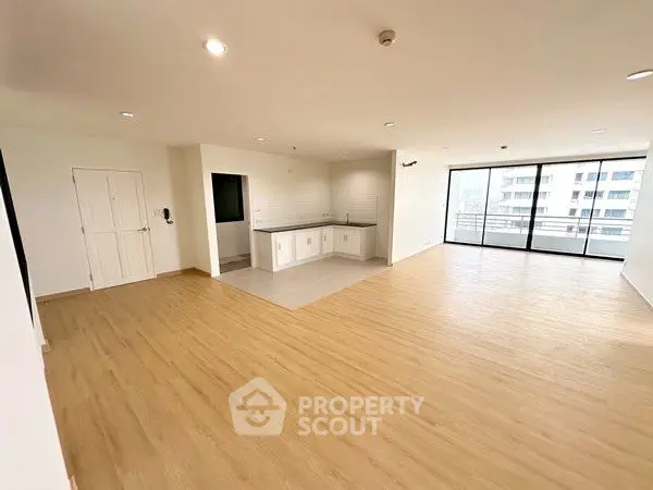 Spacious open-plan living room with modern kitchen and large balcony access.