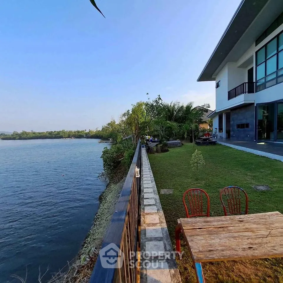 Stunning riverside property with modern architecture and lush garden, perfect for serene living.