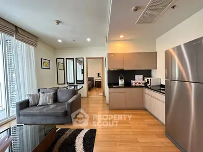 Modern open-layout living room and kitchen with sleek appliances and stylish decor.
