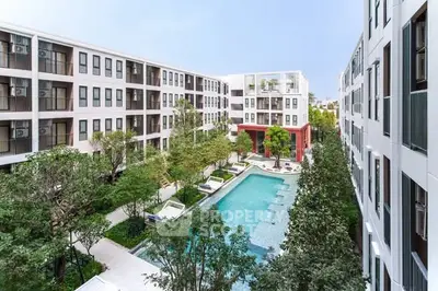 Modern apartment complex with central pool and lush greenery