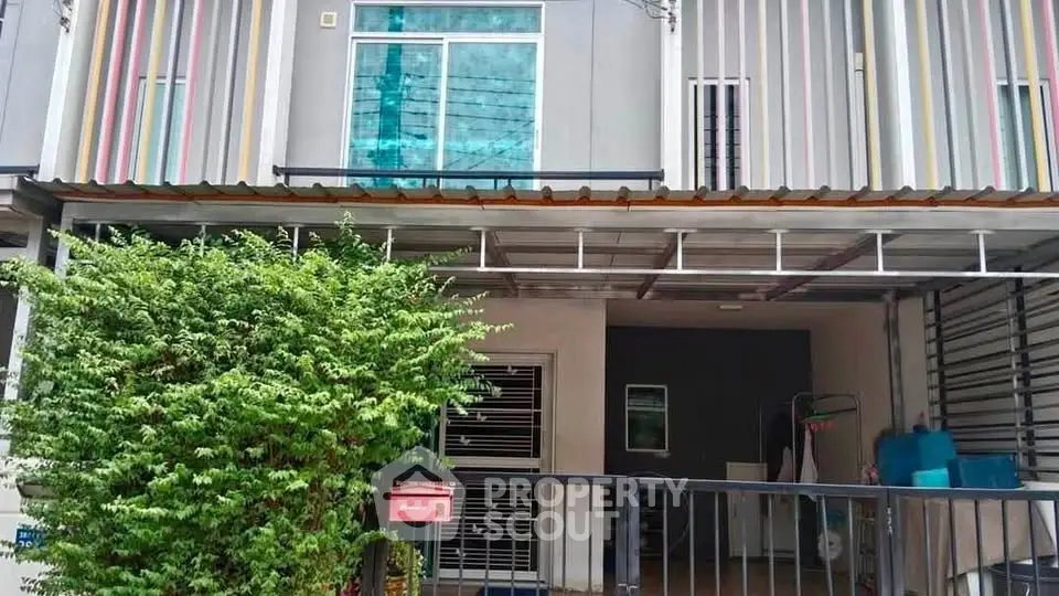 Modern townhouse exterior with gated entrance and lush greenery