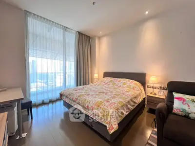 Spacious bedroom with large window and modern decor in a high-rise apartment.