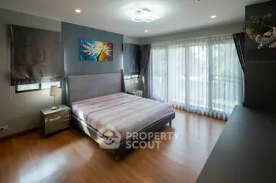 Spacious bedroom with modern decor and large windows for natural light.