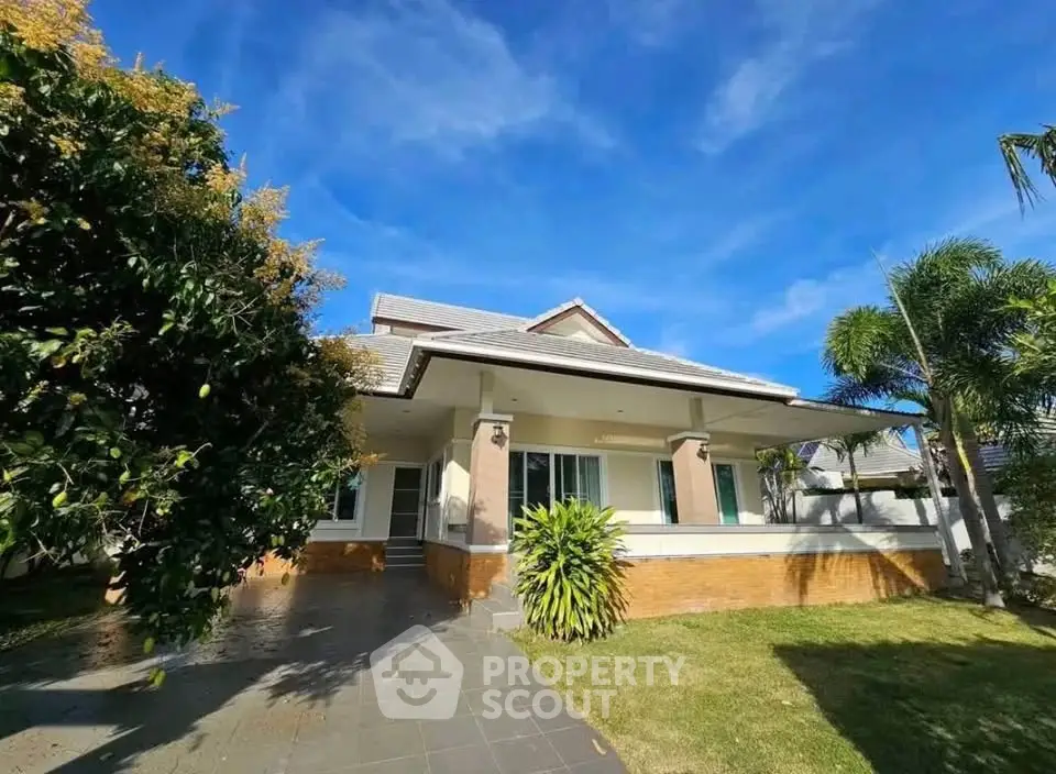Charming single-story house with lush garden and spacious front yard under a clear blue sky.