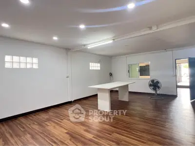 Spacious room with wooden flooring and modern lighting, ideal for versatile use.