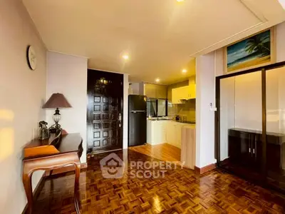 Charming open-layout living room with wooden flooring and modern kitchen.