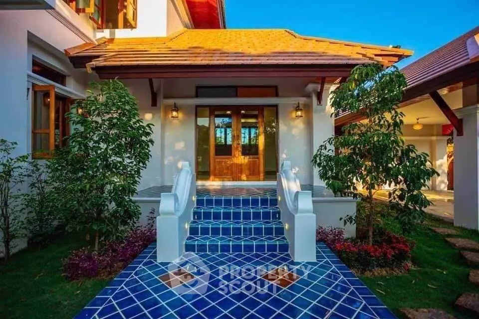 Charming entrance with vibrant blue tiled steps and lush greenery