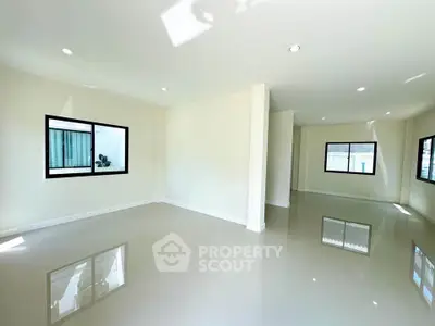 Spacious modern living room with large windows and glossy tiled floors.