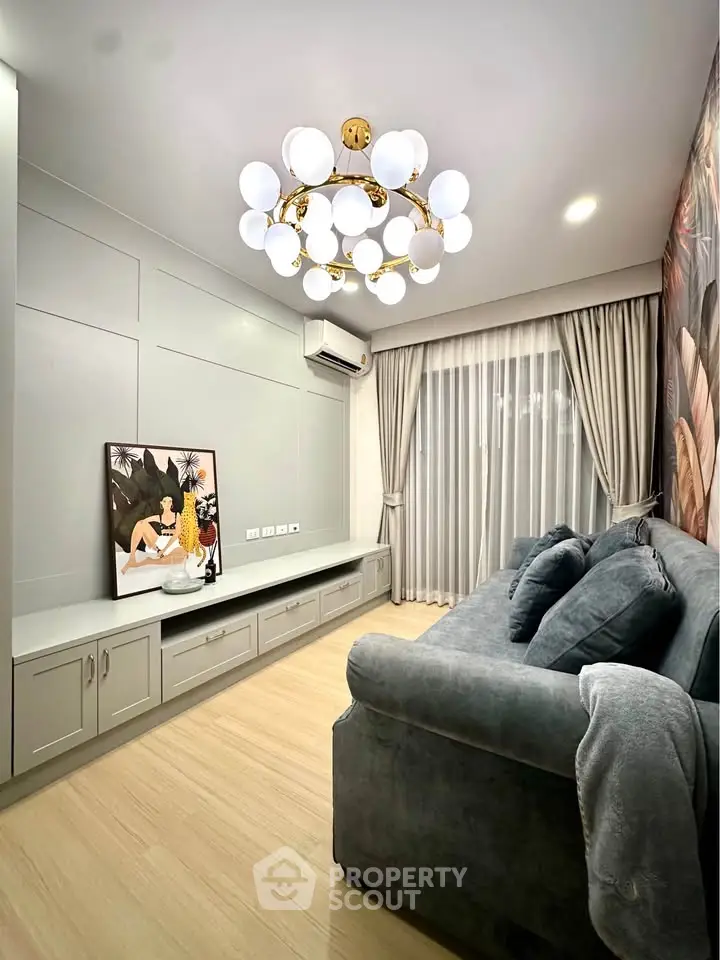 Stylish living room with modern chandelier, cozy sofa, and elegant curtains in a contemporary apartment.