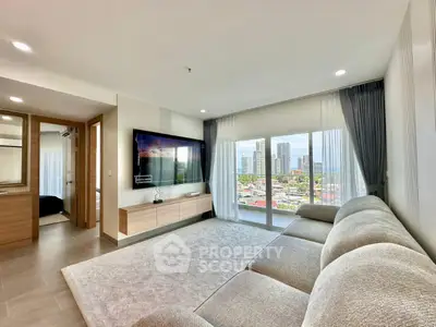 Spacious modern living room with large windows offering stunning city views, featuring a cozy sofa and sleek TV setup.