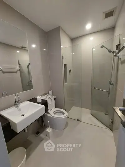 Modern bathroom with glass shower, sleek sink, and neutral tiles