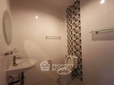 Modern bathroom with stylish tile accent wall and sleek fixtures.