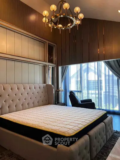 Luxurious bedroom with elegant chandelier and large windows offering natural light.