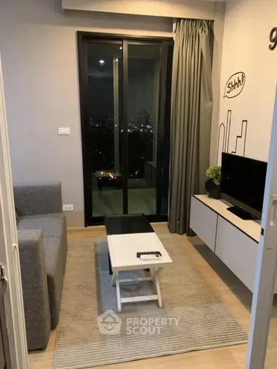 Modern living room with city view, cozy sofa, and sleek TV setup in a stylish apartment.