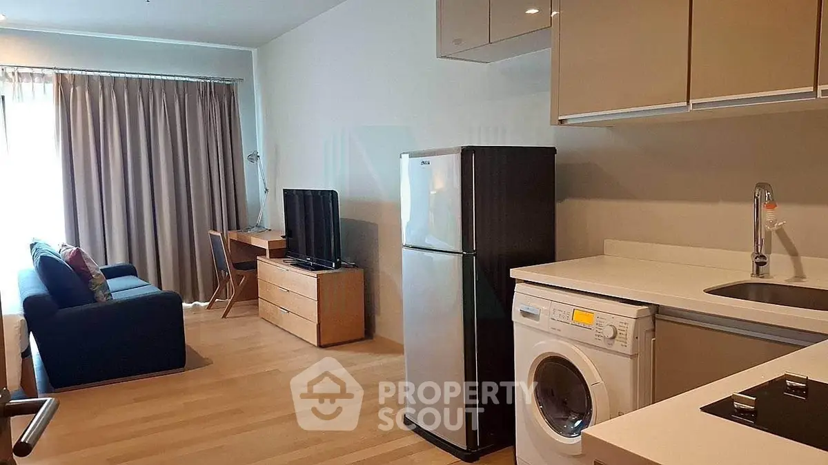 Modern studio apartment with open kitchen, washing machine, and cozy living area.