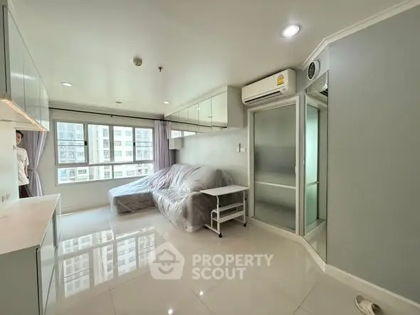 Modern living room with large windows and sleek furniture in a high-rise apartment.