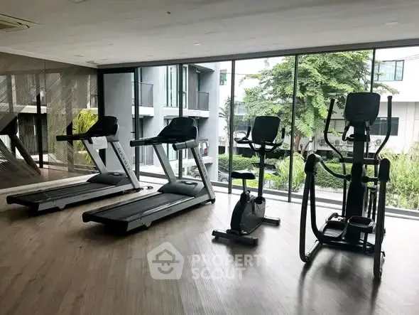 Modern gym with large windows and fitness equipment in luxury apartment building.