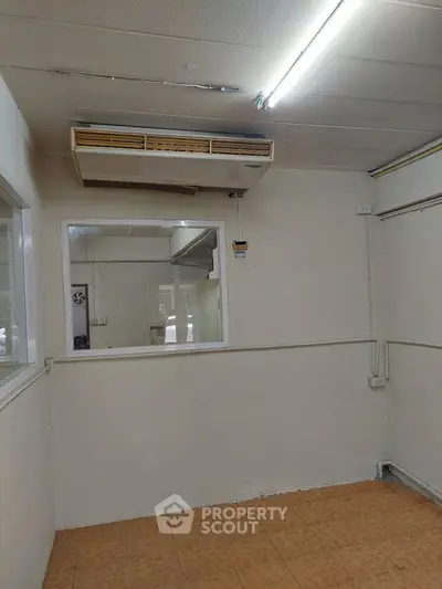 Spacious room with air conditioning and tiled flooring, ideal for office or study setup.