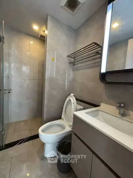 Modern bathroom with sleek fixtures and glass shower in contemporary apartment.