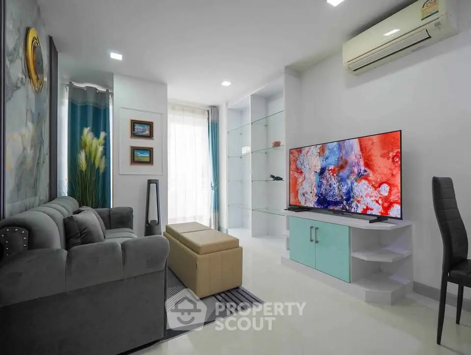 Modern living room with stylish decor, large TV, and comfortable seating in a bright, airy space.