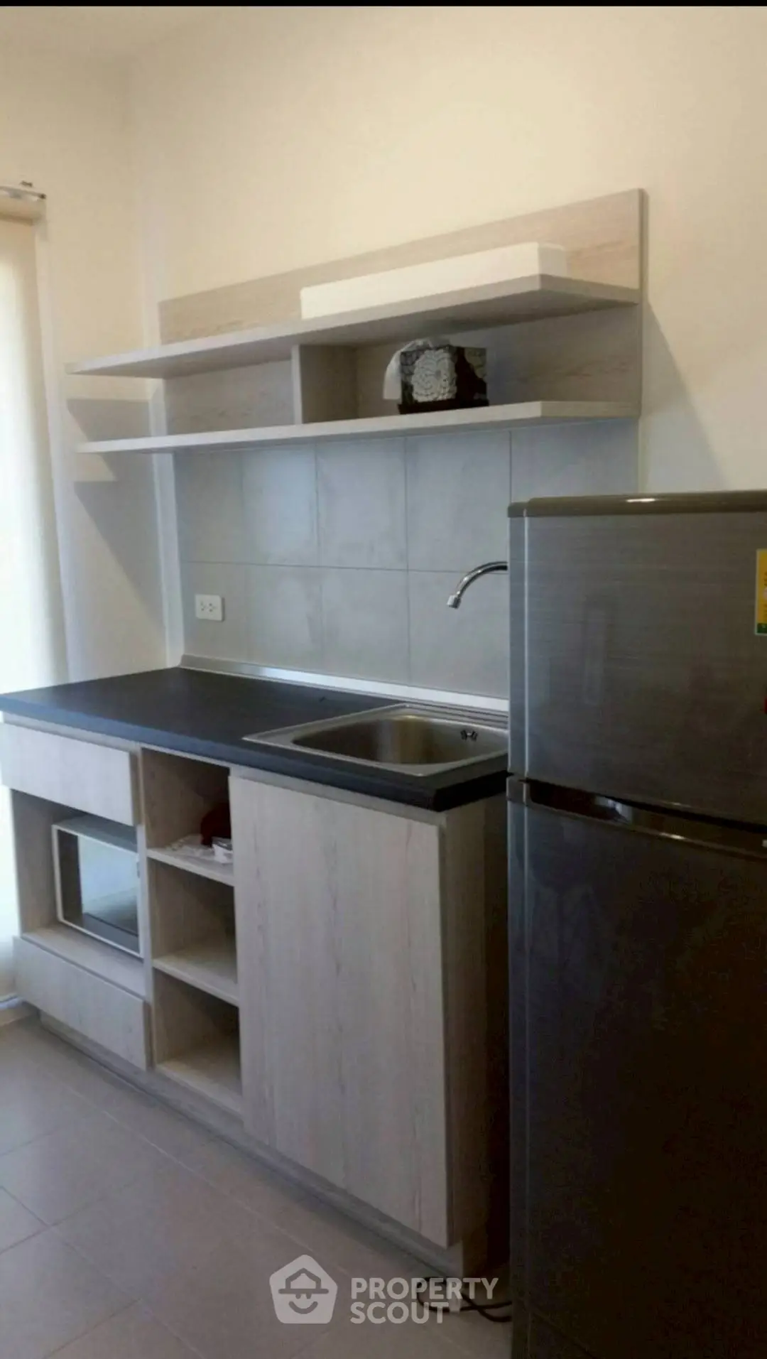 Modern kitchen with sleek cabinetry and stainless steel fridge in a compact layout.