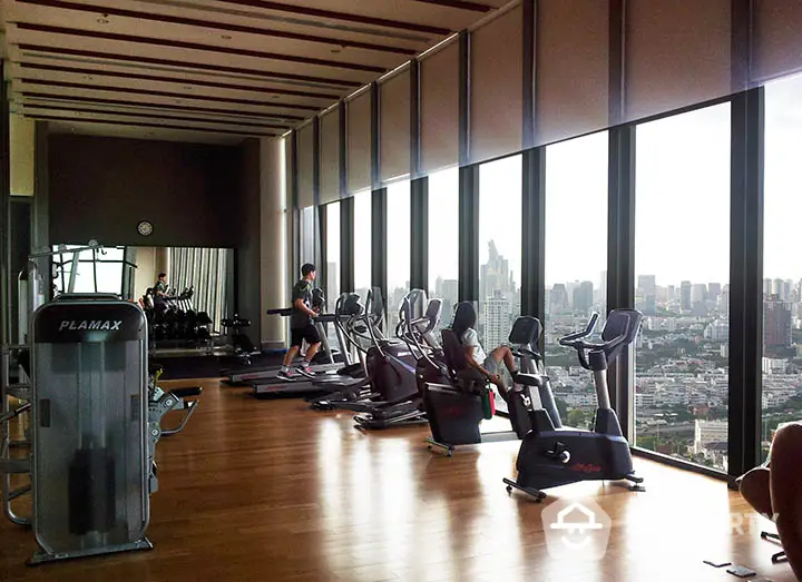 Luxurious high-rise gym with panoramic city views and modern fitness equipment.