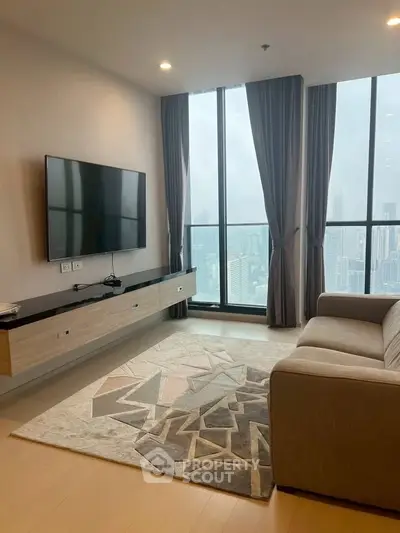 Modern living room with large windows and city view, featuring a sleek TV setup and stylish rug.