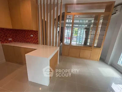 Modern open-plan kitchen with sleek cabinetry and vibrant red backsplash in a bright, spacious interior.