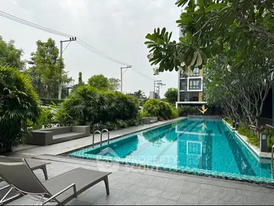 Luxurious condominium pool area with lush greenery and modern design, perfect for relaxation and leisure.