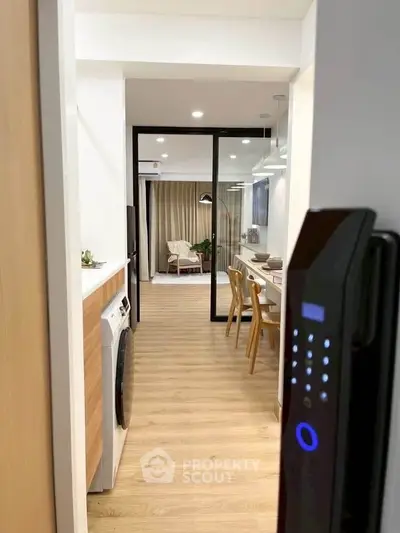 Modern apartment interior with open layout, featuring a stylish kitchen and cozy living area with wooden flooring.