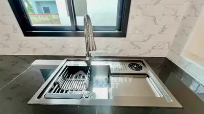 Modern kitchen sink with sleek faucet and marble backsplash in stylish home.