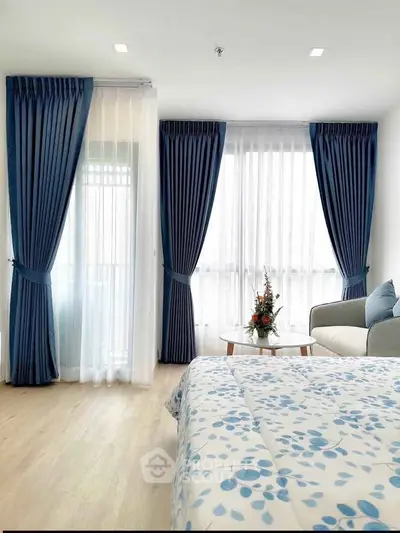Bright and airy bedroom with blue curtains and floral bedding, perfect for relaxation.