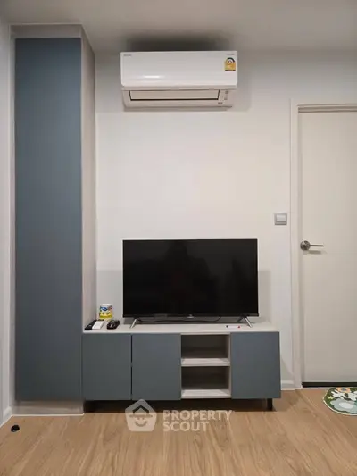 Modern living room with sleek TV unit and air conditioning, showcasing minimalist design and functionality.