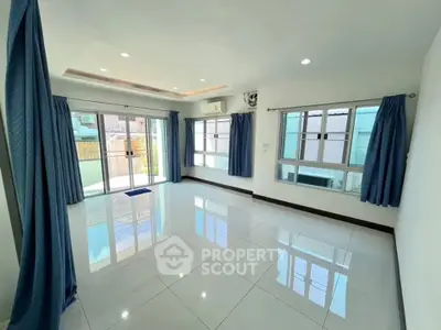 Spacious living room with large windows and blue curtains, offering ample natural light and modern design.