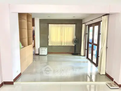 Spacious living room with large windows and modern tile flooring