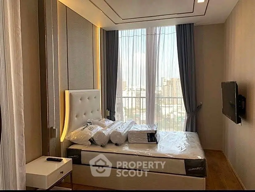 Luxurious bedroom with floor-to-ceiling windows and city view, featuring elegant decor and modern amenities.