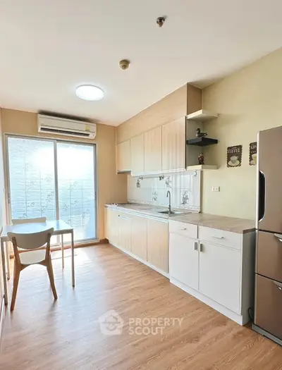 Modern kitchen with wooden flooring, sleek cabinets, and stainless steel appliances in a bright, airy space.