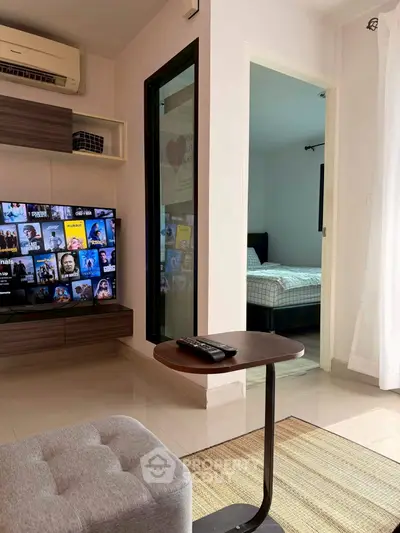 Modern living room with TV and view into cozy bedroom