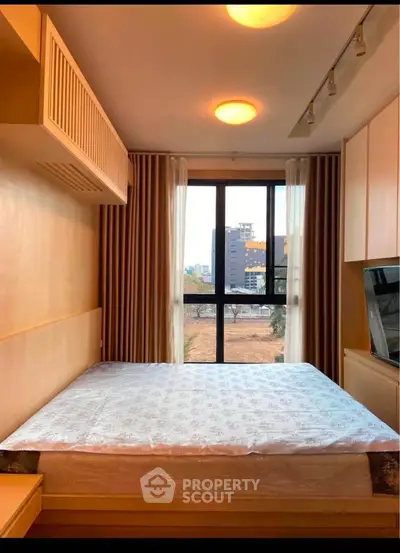 Cozy bedroom with large window offering city view, featuring modern lighting and elegant curtains.