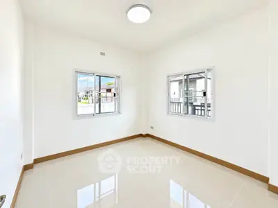 Bright empty room with large windows and glossy tiled floor in modern home.