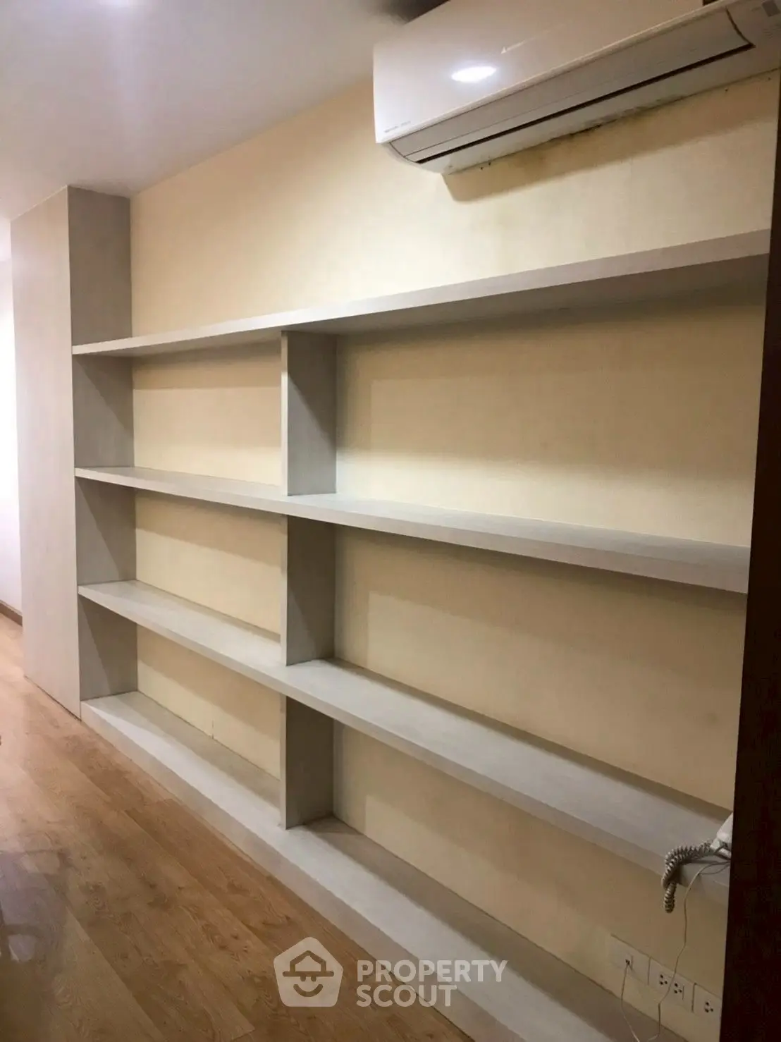 Spacious room with built-in shelves and air conditioning unit, perfect for storage or display.